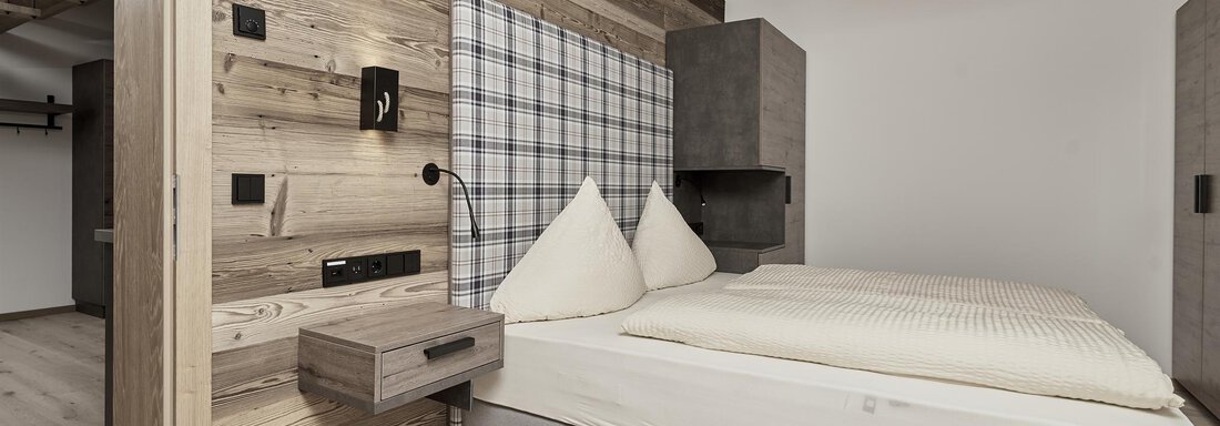 A modern bedroom with a cozy double bed and wood paneling. The walls are simply and brightly designed, creating a calming atmosphere. - The Peak Sölden - Sölden