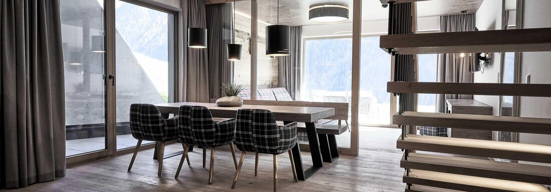 A modern dining room with a large table and stylish chairs. Large windows let in plenty of light and offer a view outside. - The Peak Sölden - Sölden