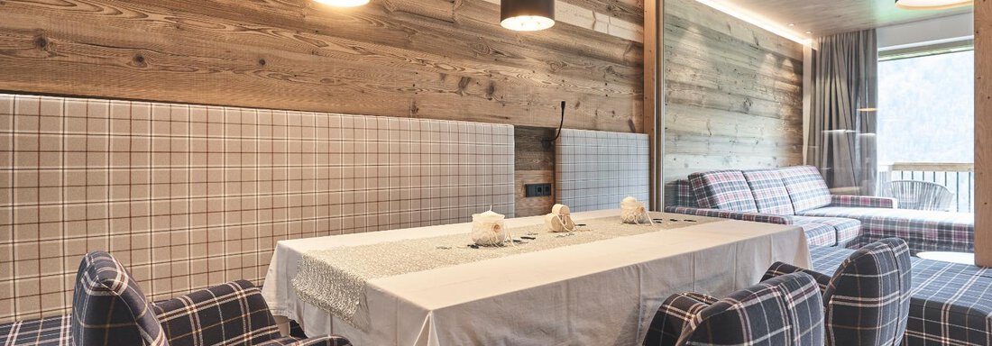 A cozy dining area with a wooden table and upholstered chairs. The walls are in warm wooden tones and the room feels welcoming. - The Peak Sölden - Sölden