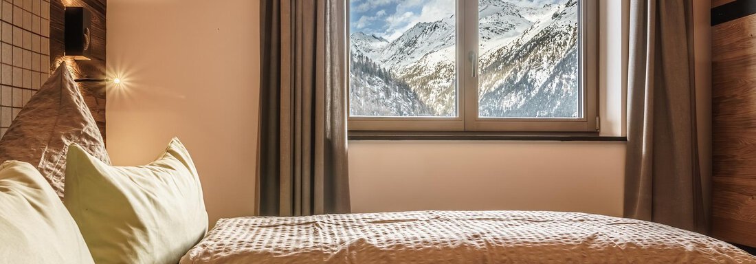 A cozy bedroom with two beds. Through the window, snow-covered mountains and a clear sky can be seen. - The Peak Sölden - Sölden