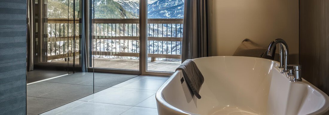 A modern bathroom with a freestanding bathtub and large windows offering a view of the mountains. The design is elegant and inviting. - The Peak Sölden - Sölden