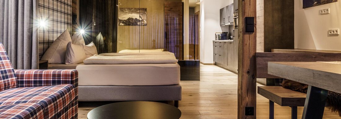 Dolomiten (1) A modern room with a cozy sofa and a large bed. The decor is warm and inviting, with wood and fabric elements. - The Peak Sölden - Sölden