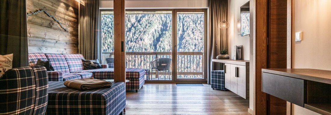 A modern living room with cozy furniture and wooden paneling. Large windows provide a view of the surroundings. - The Peak Sölden - Sölden