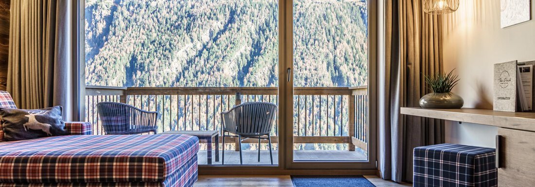 A cozy room with a large window that looks out over the mountains. There is a stylish couch and modern furniture. - The Peak Sölden - Sölden