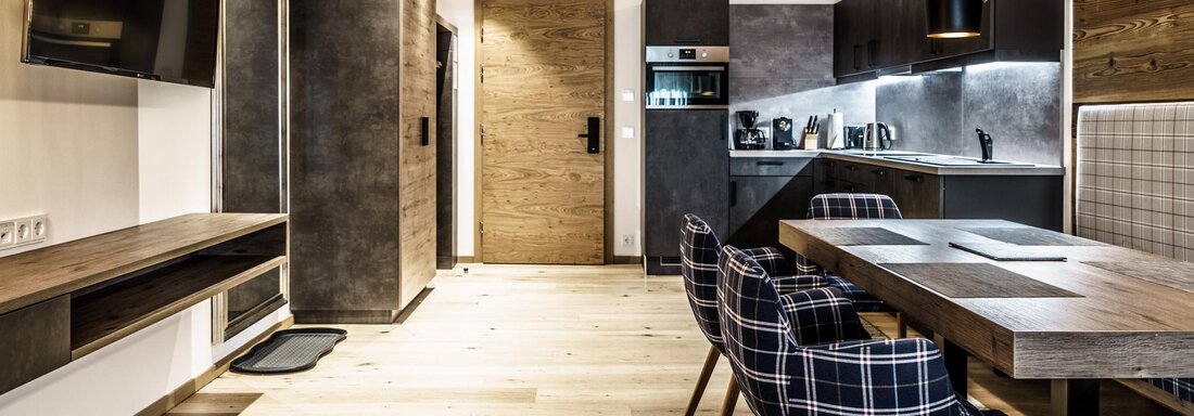 A modern kitchen with a large dining table and stylish chairs. The decor combines wood and metallic elements in a bright, inviting space. - The Peak Sölden - Sölden