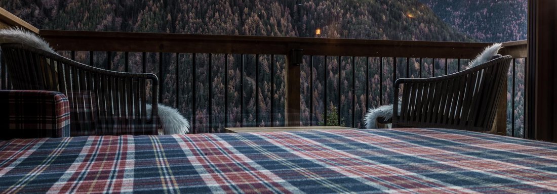 A cozy terrace with a striped table and a view of the mountains. The sun sets behind the peaks, bathing the scene in warm light. - The Peak Sölden - Sölden