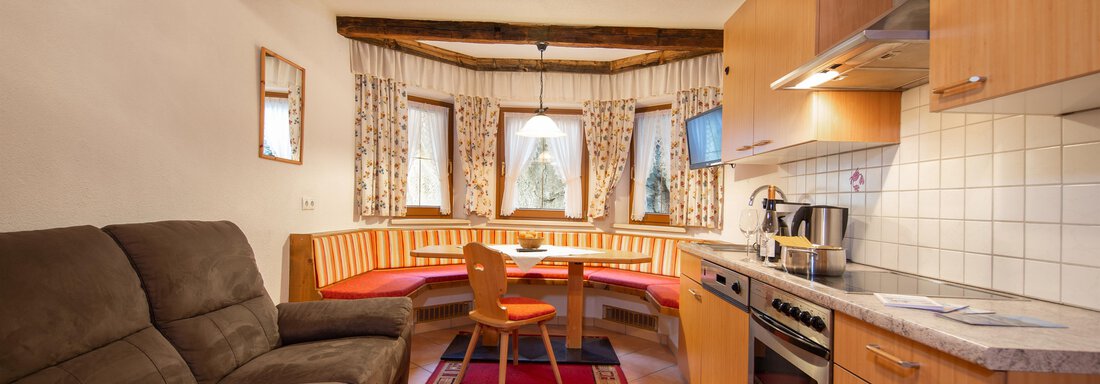 A cozy kitchen with a seating area and a sofa. The wood details and the windows create an inviting atmosphere. - Toni's Ferienheim - Sölden