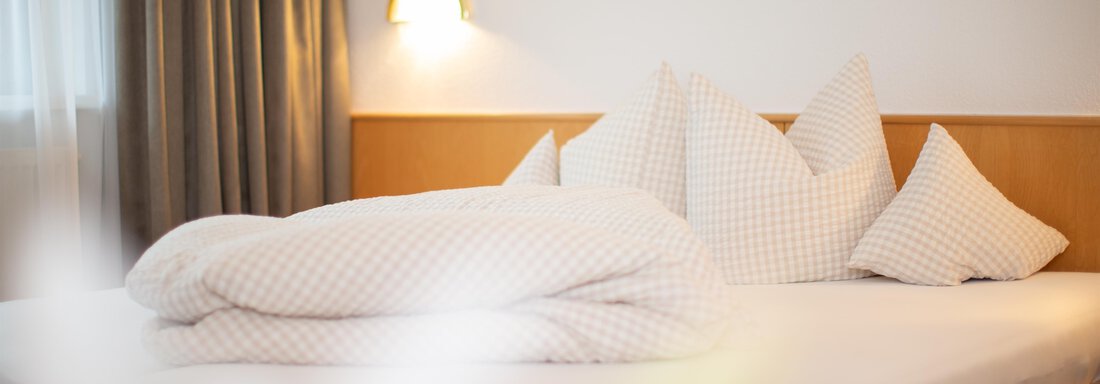 A cozy bedroom with a large bed and white pillows. Soft lighting and curtains create an inviting atmosphere. - Toni's Ferienheim - Sölden