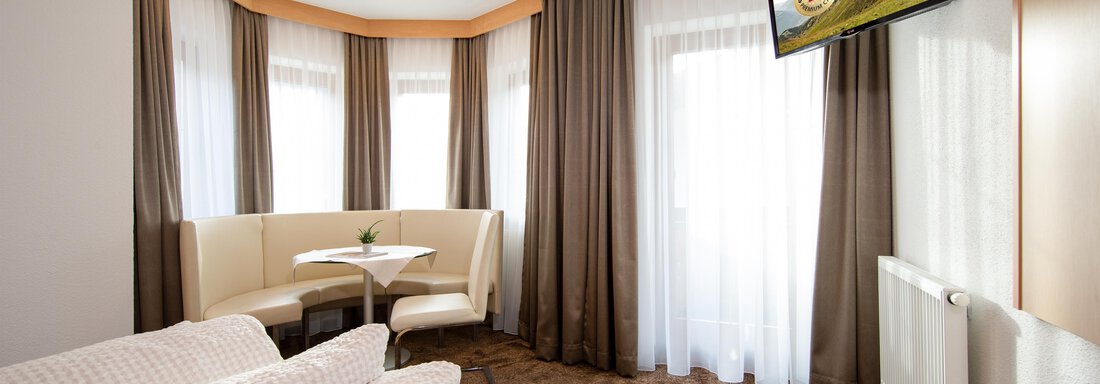 A bright room with a cozy seating area and large windows. A TV is mounted on the wall, and the decor is modern and inviting. - Toni's Ferienheim - Sölden