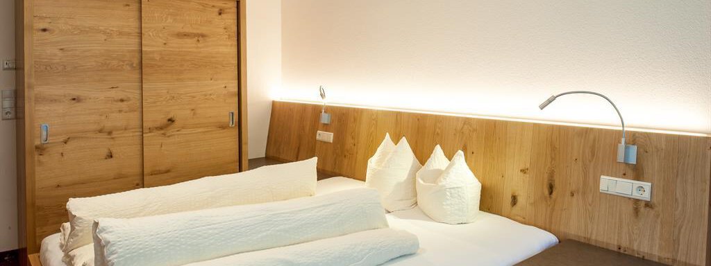 Panorama ost A cozy bedroom with a large bed and wooden shelves. Soft lighting creates a relaxed atmosphere. - Top Apart Daniela - Sölden