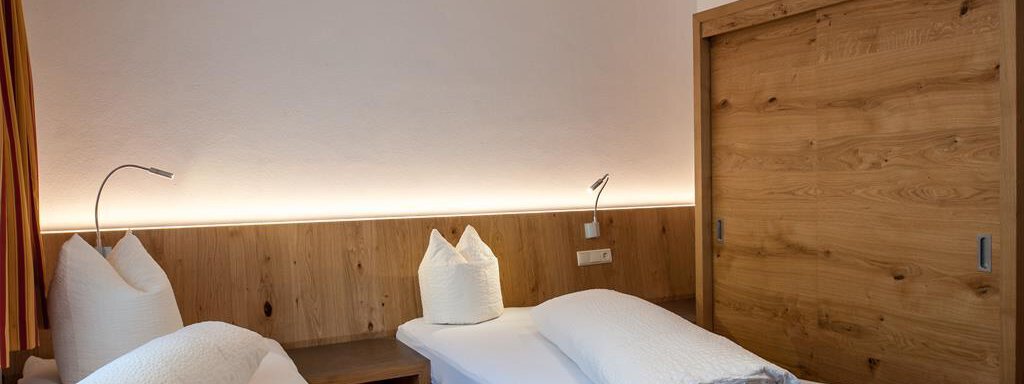 A cozy bedroom with two single beds and wooden details. The soft lighting creates a relaxed atmosphere. - Top Apart Daniela - Sölden