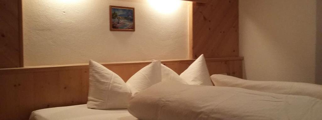 A cozy bedroom with two beds and white pillows. A small picture hangs on the wall, decorating the room. - Top Apart Daniela - Sölden