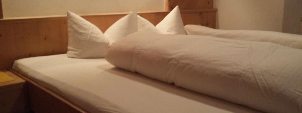A cozy bedroom with a large bed and several pillows. The walls are made of wood and there is a picture on the wall. - Top Apart Daniela - Sölden