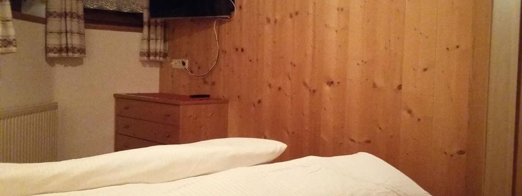 A cozy bedroom with wooden walls and a TV on the wall. Pillows and blankets are on the bed. - Top Apart Daniela - Sölden
