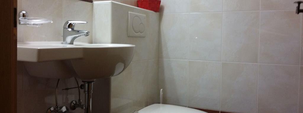 A small bathroom with a sink and a toilet. The walls are tiled in bright colors and there is a mirror above the sink. - Top Apart Daniela - Sölden