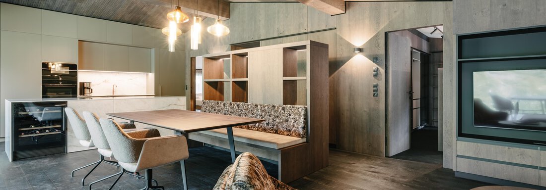 Penthouse V_Wohnzimmer_1 A modern living room with elegant design and wood paneling. The space is bright and inviting, with a cozy seating area and a dining section. - VIBES Sölden - your alpine homebase - Sölden