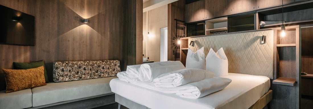 A modern hotel room with a large bed and fresh towels. A cozy seating area complements the stylish decor. - VIBES Sölden - your alpine homebase - Sölden