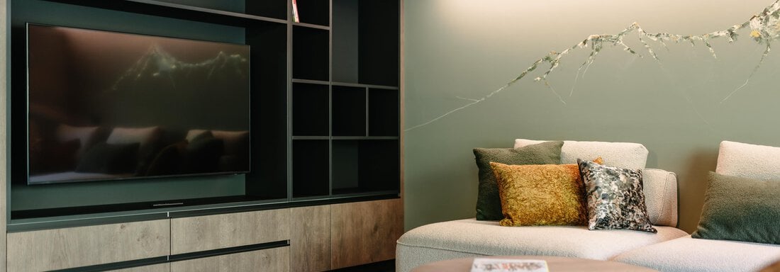 A modernly designed living room with a cozy couch and a television. The walls are painted in soft colors, and the lighting creates a pleasant atmosphere. - VIBES Sölden - your alpine homebase - Sölden