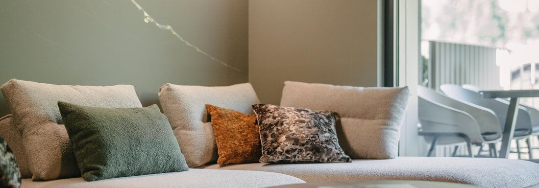A modern living room with a comfortable couch and colorful cushions. Generous windows provide plenty of daylight and a view outside. - VIBES Sölden - your alpine homebase - Sölden