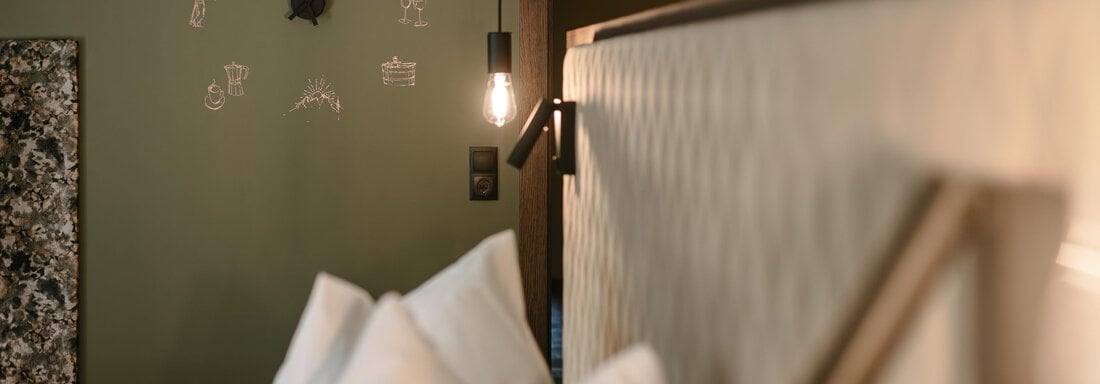 The image shows a modern bedroom with a large bed and a decorative wall. On the wall, there is a clock, and soft lighting creates a cozy atmosphere. - VIBES Sölden - your alpine homebase - Sölden