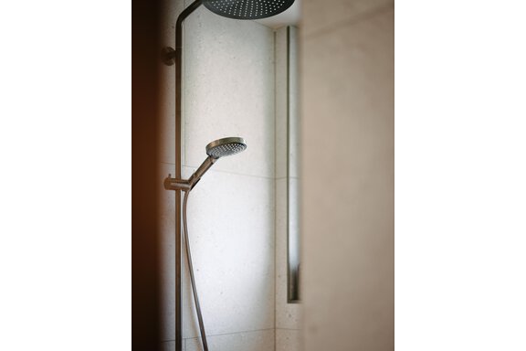 A modern shower with an elegant showerhead. The walls are made of light stone and create a relaxing atmosphere. - VIBES Sölden - your alpine homebase - Sölden