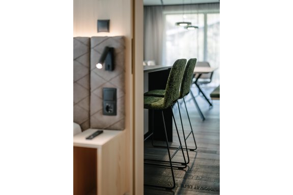 A modern furnished living space with a view of an elegant kitchenette. Two stylish bar stools are positioned at the table. - VIBES Sölden - your alpine homebase - Sölden