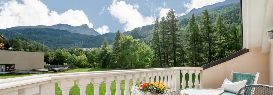 A beautiful balcony with a fantastic view of mountains and trees. The table is decorated with a flower vase. - Villa Castelbell - Sölden