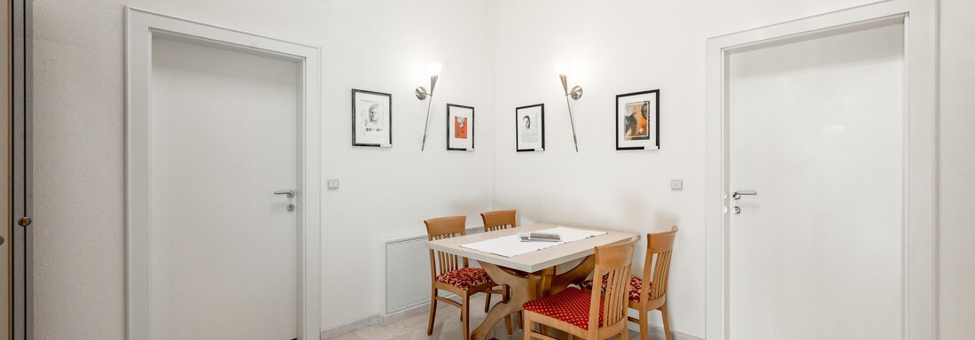 A bright room with a dining area and a table. Pictures hang on the walls and the ceiling has wooden beams. - Villa Castelbell - Sölden