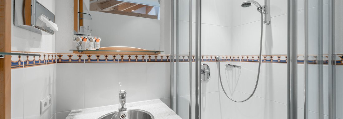 A modern bathroom with a shower and a sink. The walls are light and the room feels clean and inviting. - Villa Castelbell - Sölden