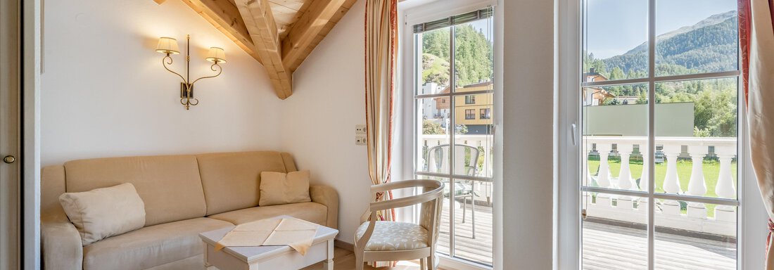 A cozy living room with a bright couch and a table.  
Large windows provide a view of the mountains. - Villa Castelbell - Sölden