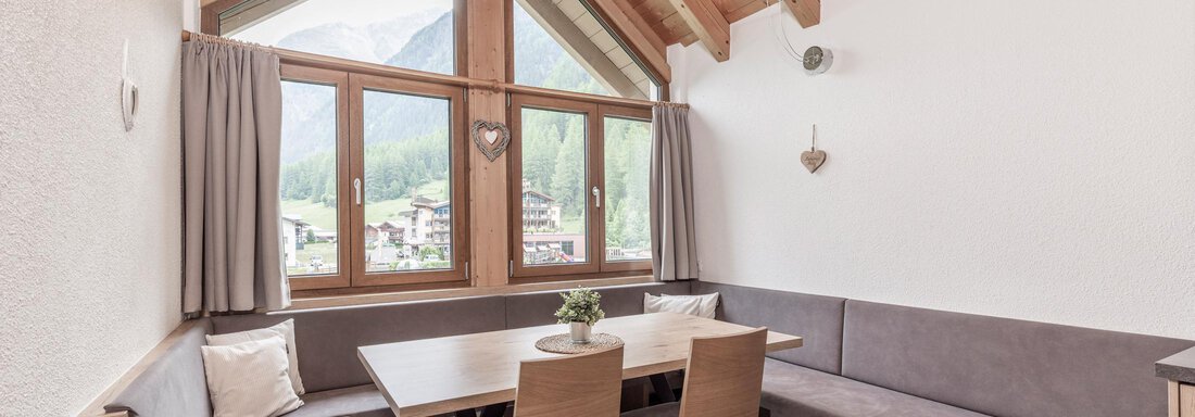 A cozy dining area with wooden tables and benches. Large windows provide a view of the mountains. - Vizensn Living - Sölden