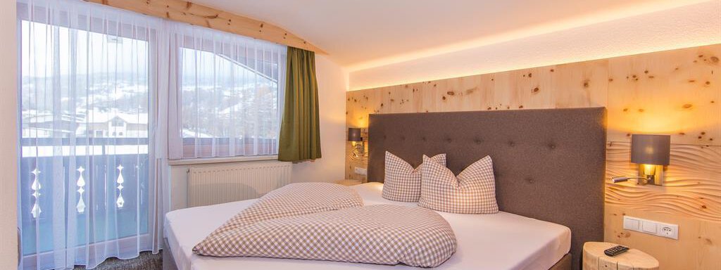 A modern bedroom with a comfortable bed and bright wood paneling. Large windows provide plenty of daylight and a beautiful view outside. - Vizensn Living - Sölden