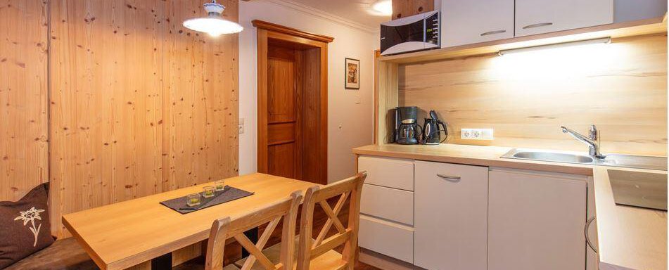 A modern kitchen with wooden details and a dining area. The room is designed to be bright and inviting. - Vizensn Living - Sölden