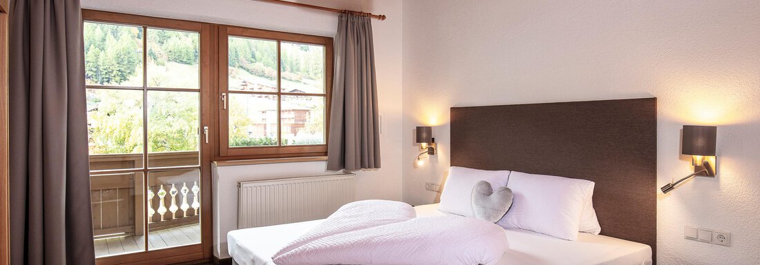 A bright and modern bedroom with a large bed and a beautiful window. The walls are light, and there is a cozy atmosphere. - Vizensn Living - Sölden