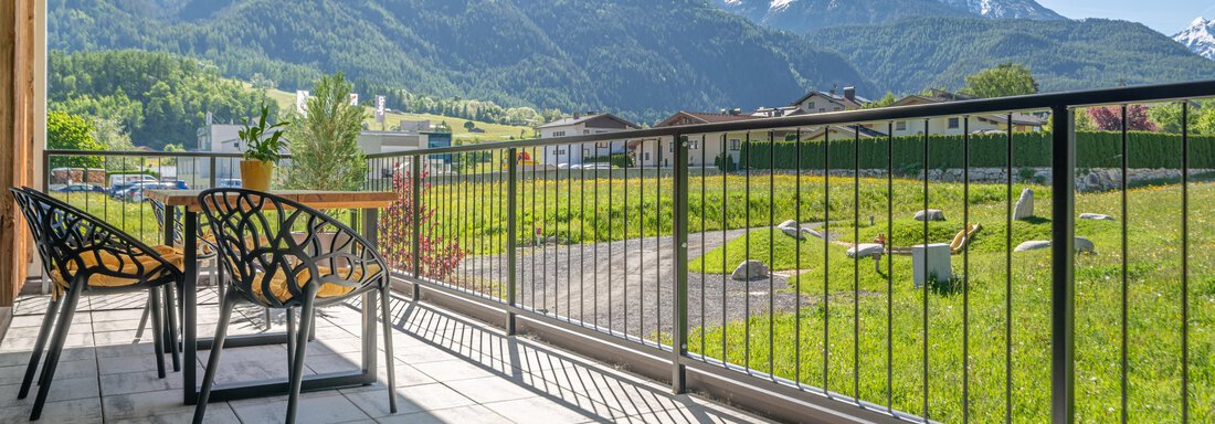 Eine gemütliche Terrasse mit Blick auf die Berge und Wiesen. Der sonnige Himmel sorgt für eine entspannte Atmosphäre. - Apart Dorhoam - Umhausen