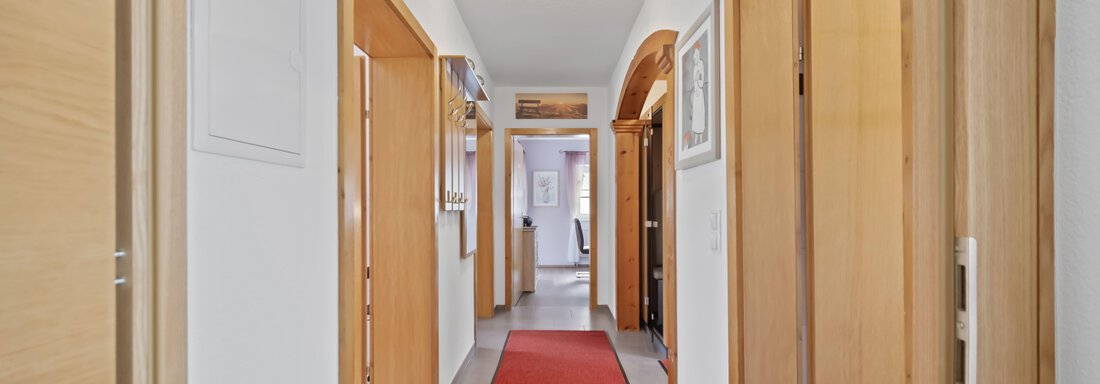 A bright hallway with wooden frames and a red carpet runner. Several doors lead to different rooms. - Biancas Ferienwohnung im Haus Roswitha - Umhausen