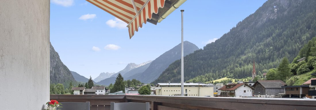 A cozy terrace with a wooden railing and a view of the mountains. The clear sky and the green hills create a relaxed atmosphere. - Biancas Ferienwohnung im Haus Roswitha - Umhausen