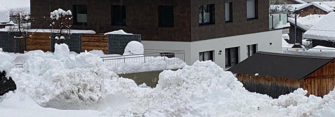 Ein modernes Haus in einem schneebedeckten Landschaft mit hohen Schneeverwehungen im Vordergrund. Die Umgebung zeigt eine ruhige, winterliche Atmosphäre. - BLANKA'S Apart Auszeit - Umhausen