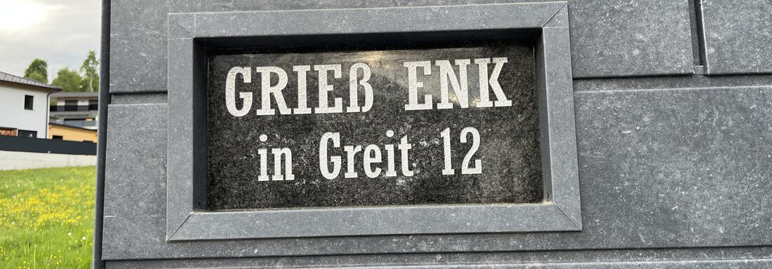 Ein Schild mit der Aufschrift "GRIEß ENK in Greit 12". Es befindet sich an einer grauen Wand. - BLANKA'S Apart Auszeit - Umhausen