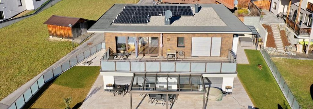 Ein modernes Haus mit Solarpanelen auf dem Dach. Es verfügt über eine große Terrasse und ist von einer grünen Umgebung umgeben. - BLANKA'S Apart Auszeit - Umhausen