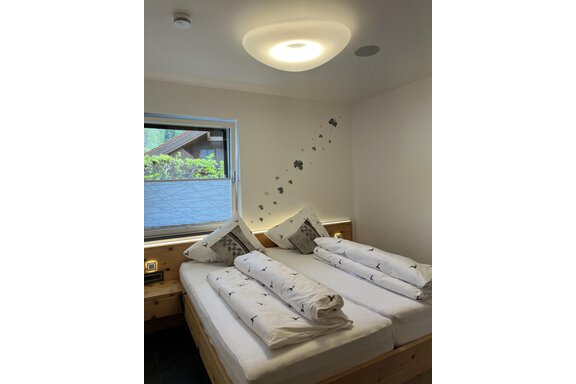 Ein gemütliches Schlafzimmer mit zwei Betten und frischen, gefalteten Handtüchern. Der Raum hat ein großes Fenster, das Tageslicht hereinlässt. - BLANKA'S Apart Auszeit - Umhausen