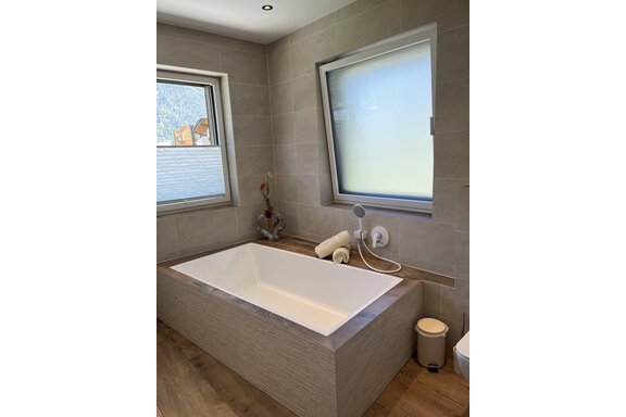 Ein modernes Badezimmer mit einer großen, rechteckigen Badewanne. Große Fenster lassen viel Licht hereinfliessen. - BLANKA'S Apart Auszeit - Umhausen