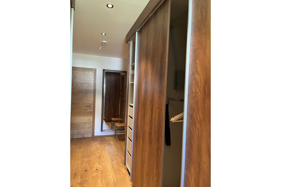 Ein moderner Flur mit Holzvertäfelung und einem Kleiderschrank. Im Hintergrund ist ein Spiegel und eine Tür sichtbar. - BLANKA'S Apart Auszeit - Umhausen