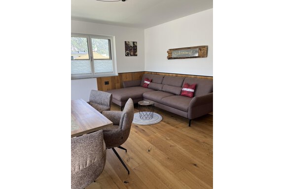 Ein modernes Wohnzimmer mit einem braunen Sofa und einem Holzsäule-Tisch. Die warmen Holzböden und das natürliche Licht sorgen für eine gemütliche Atmosphäre. - BLANKA'S Apart Auszeit - Umhausen