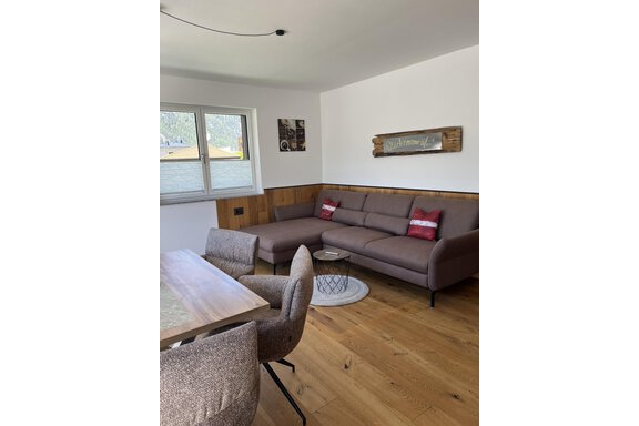 Ein modernes Wohnzimmer mit einem gemütlichen Sofa und einem Esstisch. Helle Farben und Holzdetails sorgen für eine einladende Atmosphäre. - BLANKA'S Apart Auszeit - Umhausen
