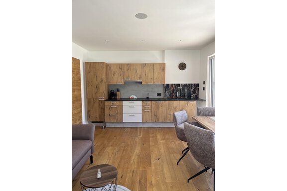 Eine moderne Küche mit Holzschränken und einer eleganten Arbeitsplatte. Der Raum ist hell und einladend, mit einem Tisch und Stühlen zur Mahlzeiten. - BLANKA'S Apart Auszeit - Umhausen
