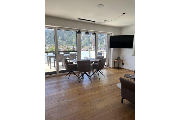 Ein modern eingerichtetes Wohnzimmer mit einem Essbereich und großen Fenstern, die auf eine malerische Aussicht blicken. Der Raum hat einen warmen Holzfußboden und eine gemütliche Atmosphäre. - BLANKA'S Apart Auszeit - Umhausen