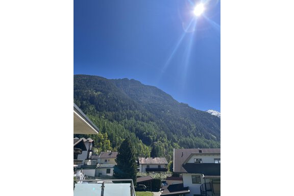 Ein klarer blauer Himmel über einem malerischen Berg. Im Vordergrund sind mehrere Häuser und Bäume sichtbar. - BLANKA'S Apart Auszeit - Umhausen