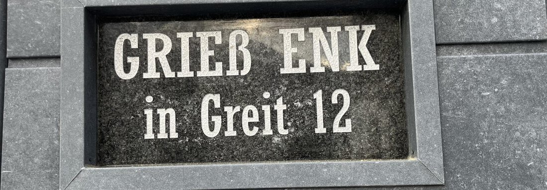 Ein Schild mit der Aufschrift "GRIEß ENK in Greit 12". Das Schild ist auf einem grauen Hintergrund angebracht. - BLANKA'S Apart Auszeit - Umhausen