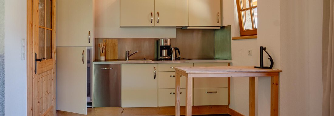 A modern kitchen with white cabinets and a wooden worktop. The room design is bright and cozy. - Chalet Carla - Umhausen